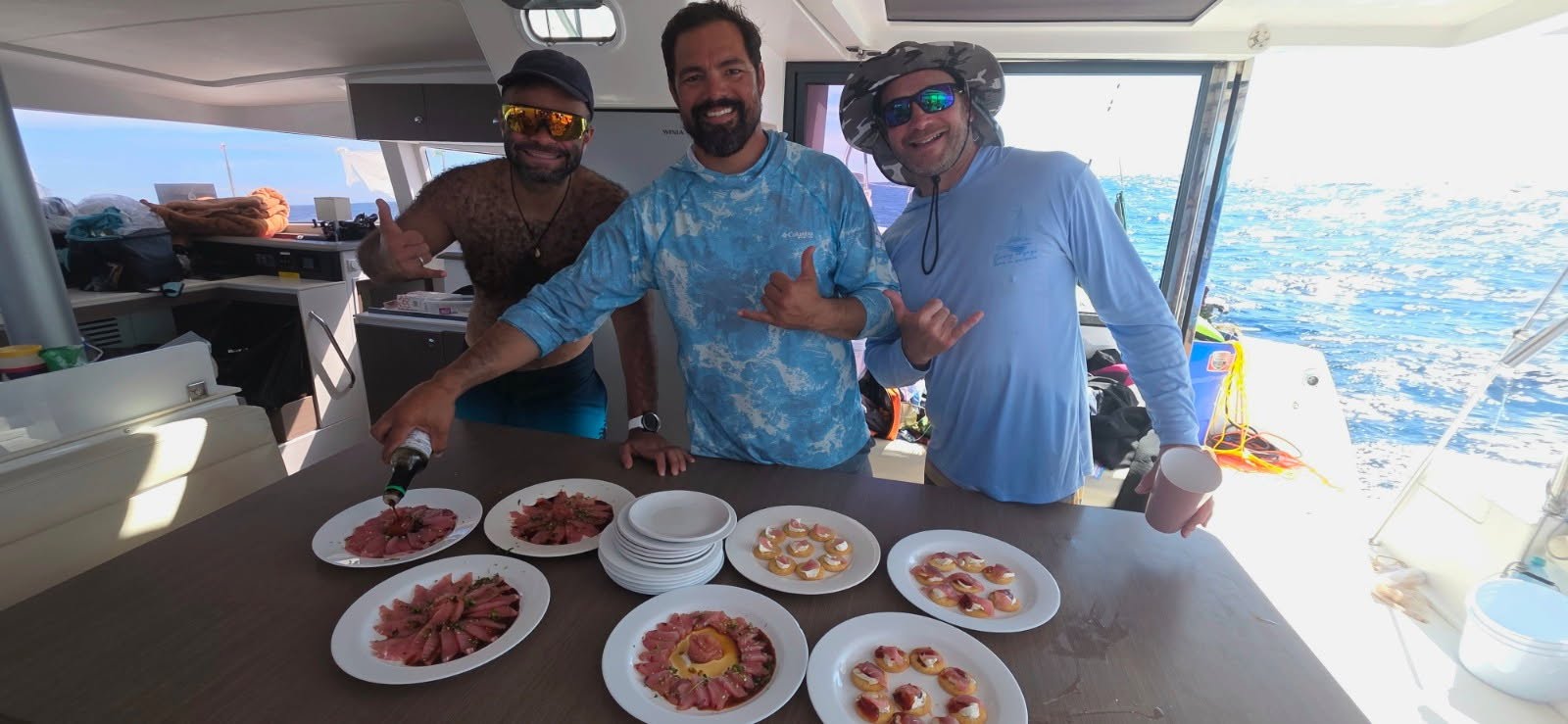 Guests sharing plates of fresh fish aboard a catamaran